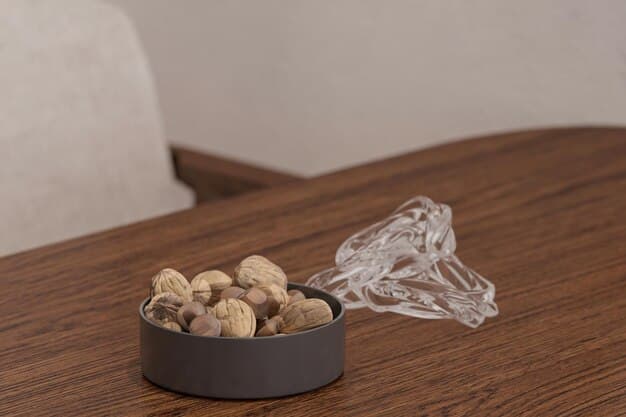 A close-up of a glass of water and a small bowl of nuts on a desk.