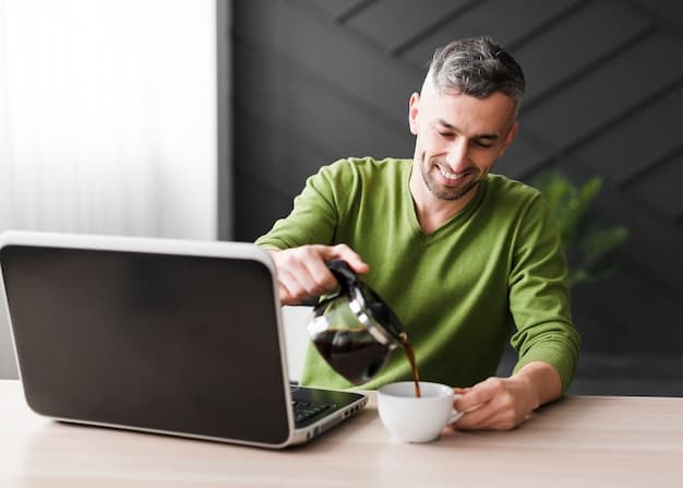 A person focused on their laptop with a cup of coffee