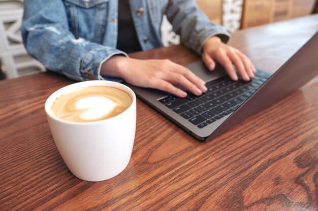 A person typing on a laptop, with a cup of coffee nearby