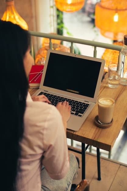 A person working on a laptop in a cozy coffee shop setting with a drink on the table.
